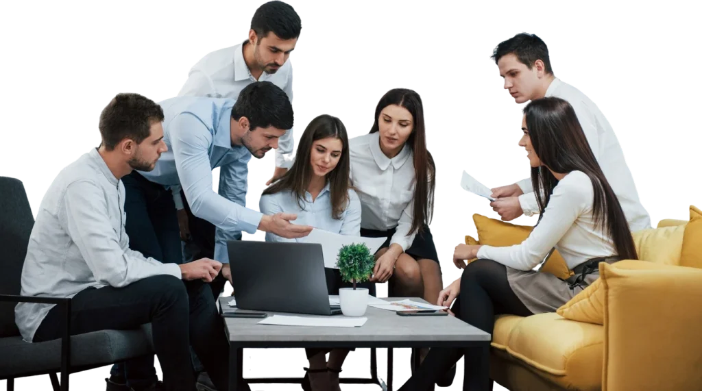 Equipo de trabajo revisando documentos alrededor de una laptop